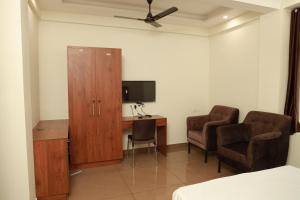 科钦Grace Apart Hotel @Kochi的客房设有书桌、橱柜和2把椅子。
