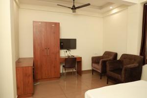 科钦Grace Apart Hotel @Kochi的配有书桌、两把椅子和电视的房间