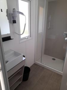 滨海拉普兰mobil home neuf dans camping 4* avec piscine的带淋浴和盥洗盆的白色浴室