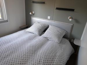 滨海拉普兰mobil home neuf dans camping 4* avec piscine的卧室配有白色的床和2个枕头
