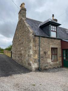 Wester FearnQuirky Highland Cottage with Stunning Views的一座古老的石头建筑,设有绿门