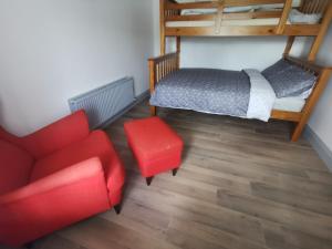韦克斯福德Orchard Cottage的一间卧室配有一张床和一张红色椅子