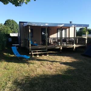 滨海拉普兰mobil home neuf dans camping 4* avec piscine的小屋设有甲板、桌子和椅子