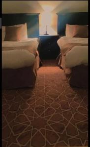 萨维奇هتان السودة Hattan Al-Sodah的一间卧室配有两张床和一张带台灯的桌子