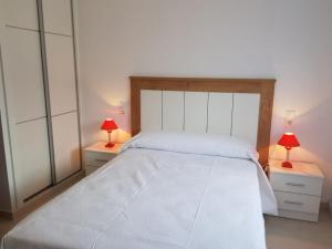 桑亨霍Chalet Major Beach Sanxenxo的一间卧室配有一张带两盏灯的大型白色床。