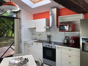 贝尔热拉克Chambres & Tables d'Hôtes L'Ostal de Pombonne的厨房配有白色橱柜和红色墙壁