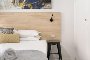 AdamstownAdamstown Short Stay Apartments的一间卧室配有一张带木制床头板和凳子的床。