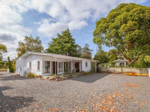 WaitahanuiLake Edge Cottage - Waitahanui Holiday Home的砾石车道上的白色小房子