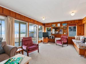 WaitahanuiLake Edge Cottage - Waitahanui Holiday Home的客厅配有沙发和两把椅子