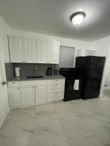 迈阿密Guest house near Downtown Miami的厨房配有白色橱柜和黑色冰箱。
