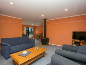 陶波Laid Back on Lakewood - Taupo Holiday Home的客厅配有蓝色的沙发和咖啡桌