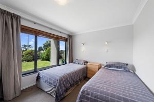 帕帕莫阿The Sandcastle - Papamoa Holiday Apartment的卧室设有两张床和大窗户