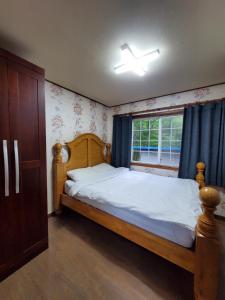 平昌平昌梅发纳沙度假屋的一间卧室设有一张木床和一个窗户。