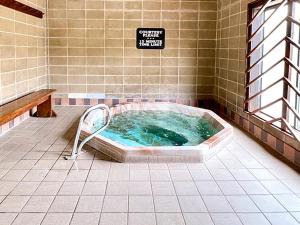 雷德洛治贝尔图斯度假酒店加小屋的带有标志的浴室内的按摩浴缸