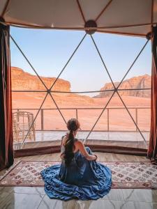 瓦迪拉姆Bubble RumCamp的坐在地上看着沙漠的年轻女孩