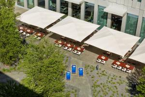 慕尼黑H2 Hotel München Messe的享有带桌子和白色遮阳伞的建筑的顶部景色