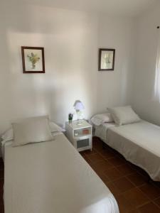塔里法Finca Dos Vientos Tarifa的客房设有两张床和一张带台灯的桌子。