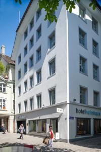 苏黎世Boutique Hotel Helmhaus Zürich的一座白色的建筑,前面有一位妇女