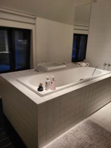哈勒Gezellige moderne woning met zwemvijver的浴室配有带镜子的大型白色浴缸