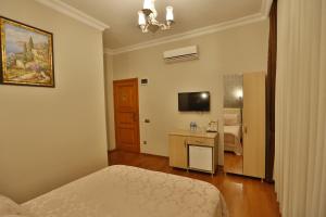 比于卡达Mimoza Butik Otel Buyukada的一间卧室配有一张床、一张书桌和一台电视