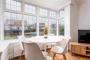 艾尔Wellington View - Donnini Apartments的一间设有白色桌子、椅子和窗户的用餐室