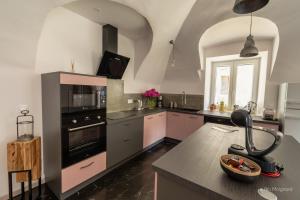 勒布罗伊斯Le Manoir, appartement Beryl的厨房配有粉色和黑色电器和桌子