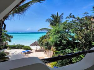 南威桑给巴尔酒店的享有海滩和大海的美景,设有蓝色长椅。