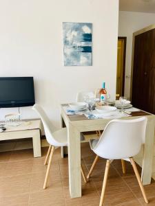 切尔诺莫雷茨Апартамент в комплекс Свети Никола плаж Градина的一间带木桌和白色椅子的用餐室