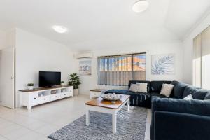 曼哲拉Avalon Beach Escape ~ Family Favourite with Wifi的客厅配有蓝色的沙发和桌子