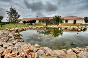 奥德赛克斯Monte Joao Roupeiro - Turismo Rural的一座房子前面的池塘,有一座建筑