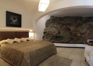 阿诺吉亚德里纳群山度假村的一间卧室设有一张床和一个大型岩石墙