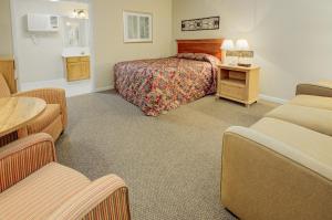 赛维尔维尔Mountain Aire Inn Sevierville - Pigeon Forge的酒店客房带一张床、一张桌子和椅子