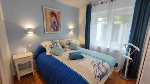 布里夫拉盖亚尔德Le Petit Paradis的卧室配有蓝色和白色的床,设有窗户