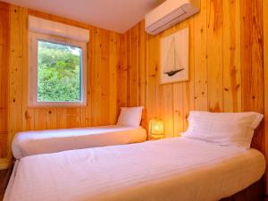 卡普费雷Résidence Les Suites Du Ferret的配有木墙和窗户的客房内的两张床
