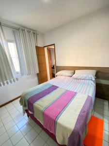 瓜拉派瑞Apt temporada guarapari的一间卧室配有一张带彩色条纹毯子的床