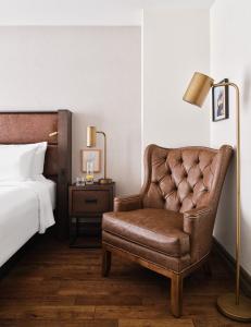 渥太华The Metcalfe by Gray Collection的一间卧室配有床和棕色皮椅