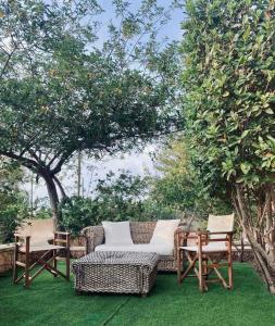KhlóïSeaside "Stone & Light Villa II" close to Aegina City的庭院设有两把椅子、一个柳条沙发和桌子