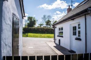 唐帕特里克The Heights & Hollows Farmhouse, Saul, Downpatrick, SLEEPS 14的白色的建筑,有门和车道