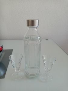 蒂瓦特Apartmani Bosco的桌子上放有玻璃瓶和两杯