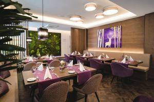 巴登-巴登默克高级酒店的餐厅配有紫色桌椅和绘画作品
