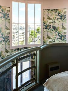 巴黎Hôtel Mercedes的一间卧室设有床、两个窗户和一个阳台