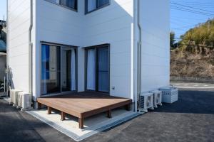 佐世保Rakuten STAY HOUSE x WILL STYLE Sasebo 102的房屋的一侧设有木凳