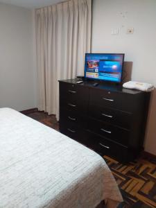 利马Apart Hotel Don Ernesto的一间卧室配有一张床,梳妆台上配有电视
