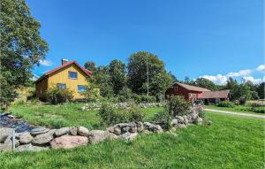 SvanesundNice Apartment In Svanesund With House Sea View的院子中一座黄色的房子,有石墙