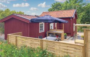 TystbergaGorgeous Home In Tystberga With Kitchen的木制甲板上带雨伞的红色棚子