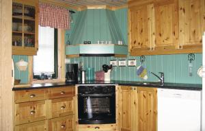 Stakkeland5 Bedroom Amazing Home In Kvinlog的厨房配有木制橱柜和黑炉灶烤箱。