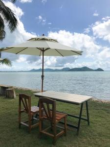 瑶亚岛Koh Yao Yai Sea Breeze House เกาะยาวใหญ่ซีบรีซเฮ้าส์的水边伞下的桌椅