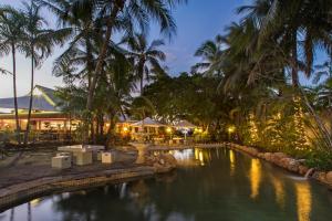 汤斯维尔Seagulls的棕榈树度假村的游泳池以及餐厅