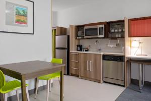 巴吞鲁日Home2 Suites By Hilton Baton Rouge Citiplace的一间带桌子的小厨房和一间带冰箱的厨房