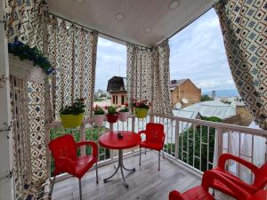 第比利斯洛厄尔酒店的阳台配有红色椅子、桌子和窗户。